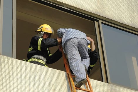 Feuerwehrmänner retten einen Mann aus dem Fenster